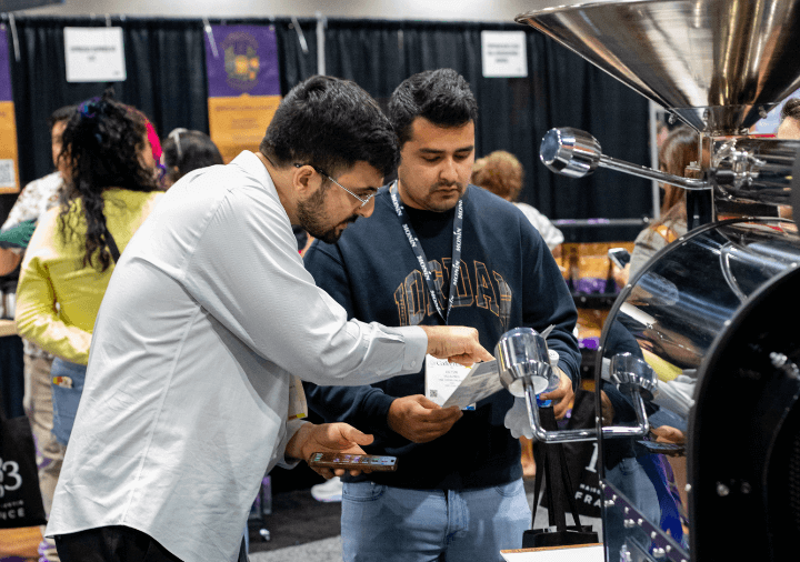 Roasting equipment exhibitor explaining advantages to an attendee at their booth on the show floor