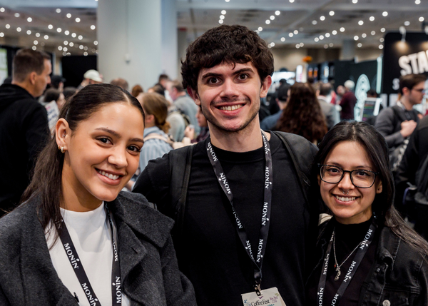 Three attendees on the show floor smiling at the camera