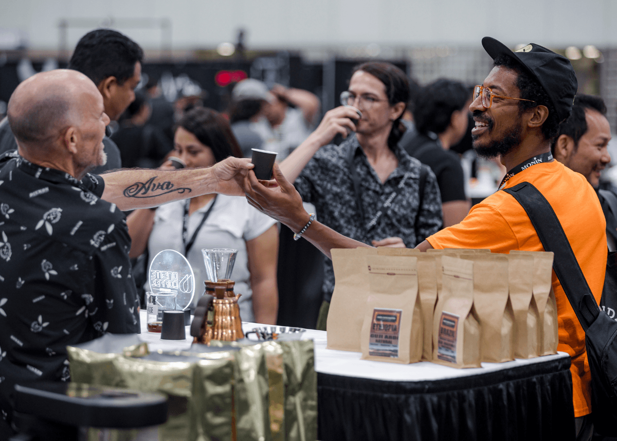 Exhibitor smiling and handing sample to attendee