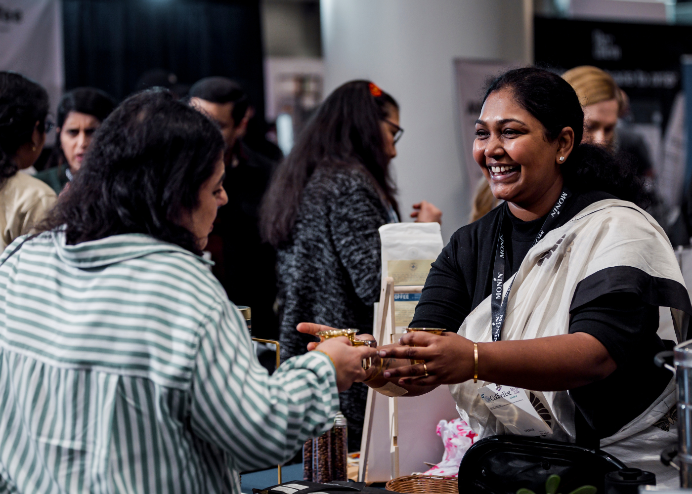 Exhibitor smiling and handing attendee a sample