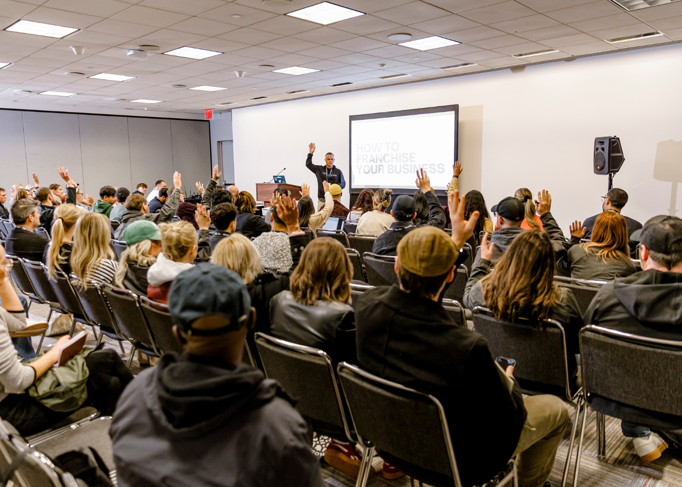 Lecture with attendees raising their hands