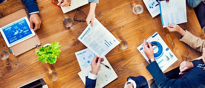 Professionals working around a table with important documents strewn about