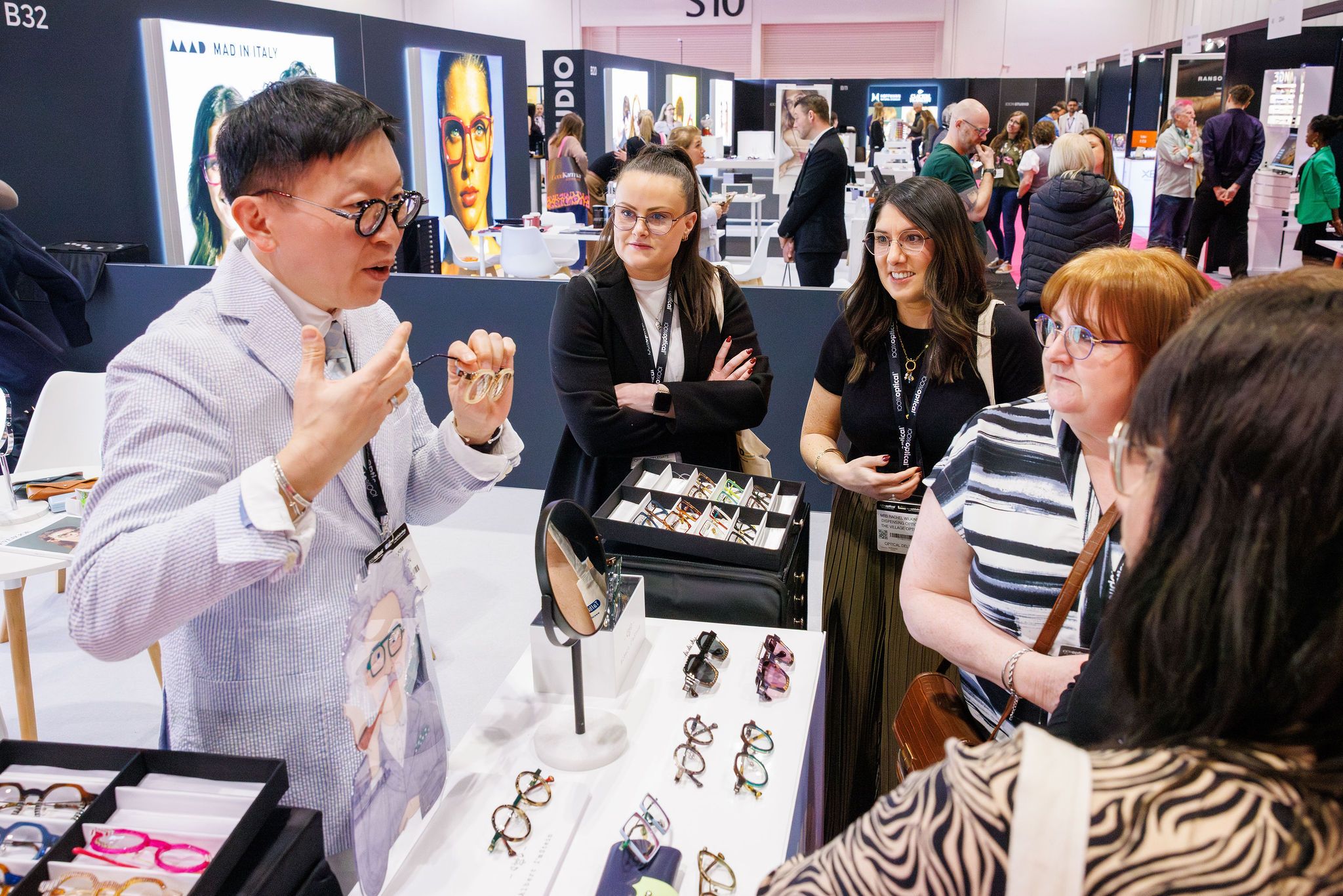 A group of people in discussion over a selection of frames at 100% Optical. 