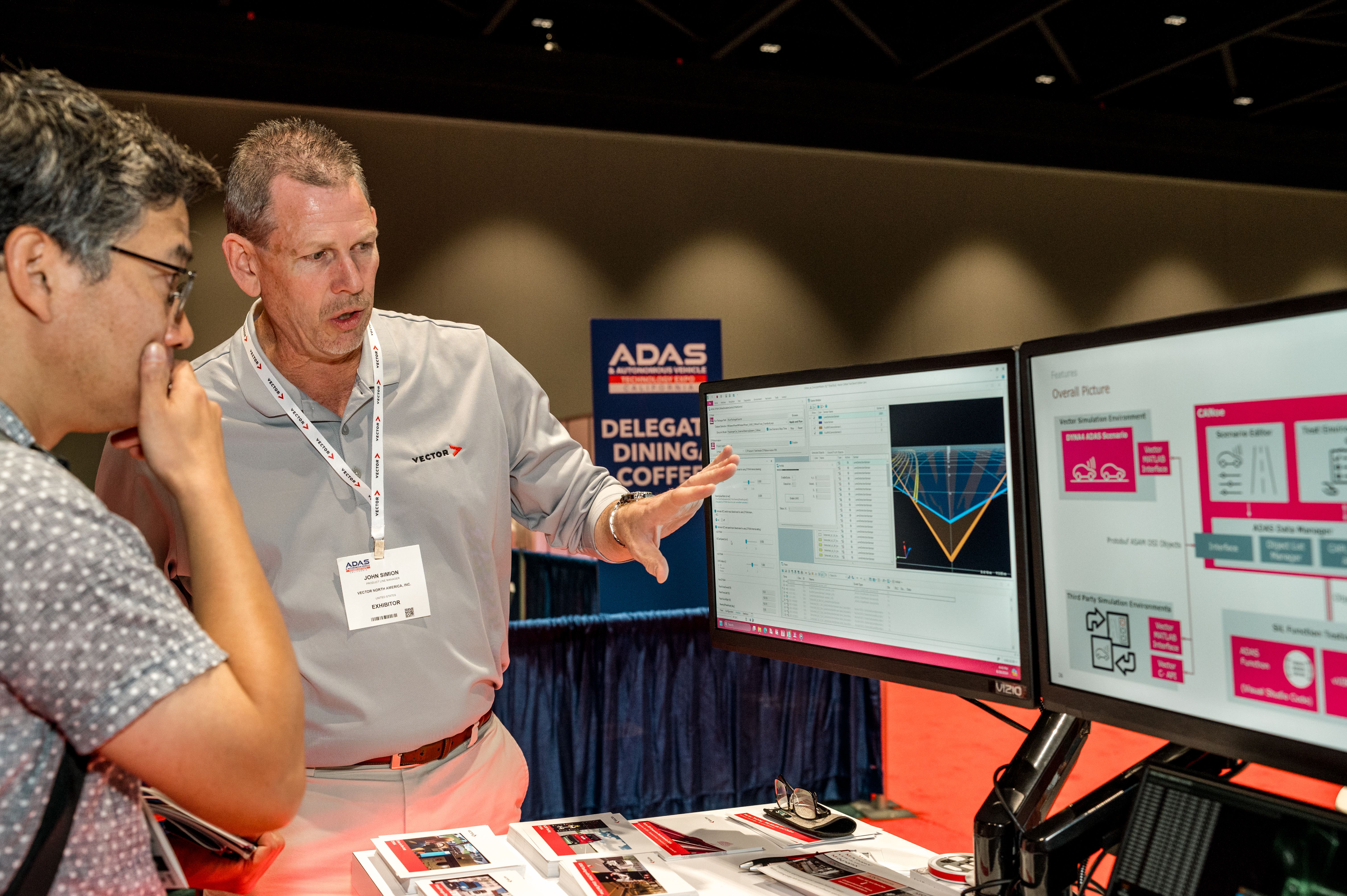 Photo shows an exhibitor in discussion with a visitor at ADAS & AV Technology Summit