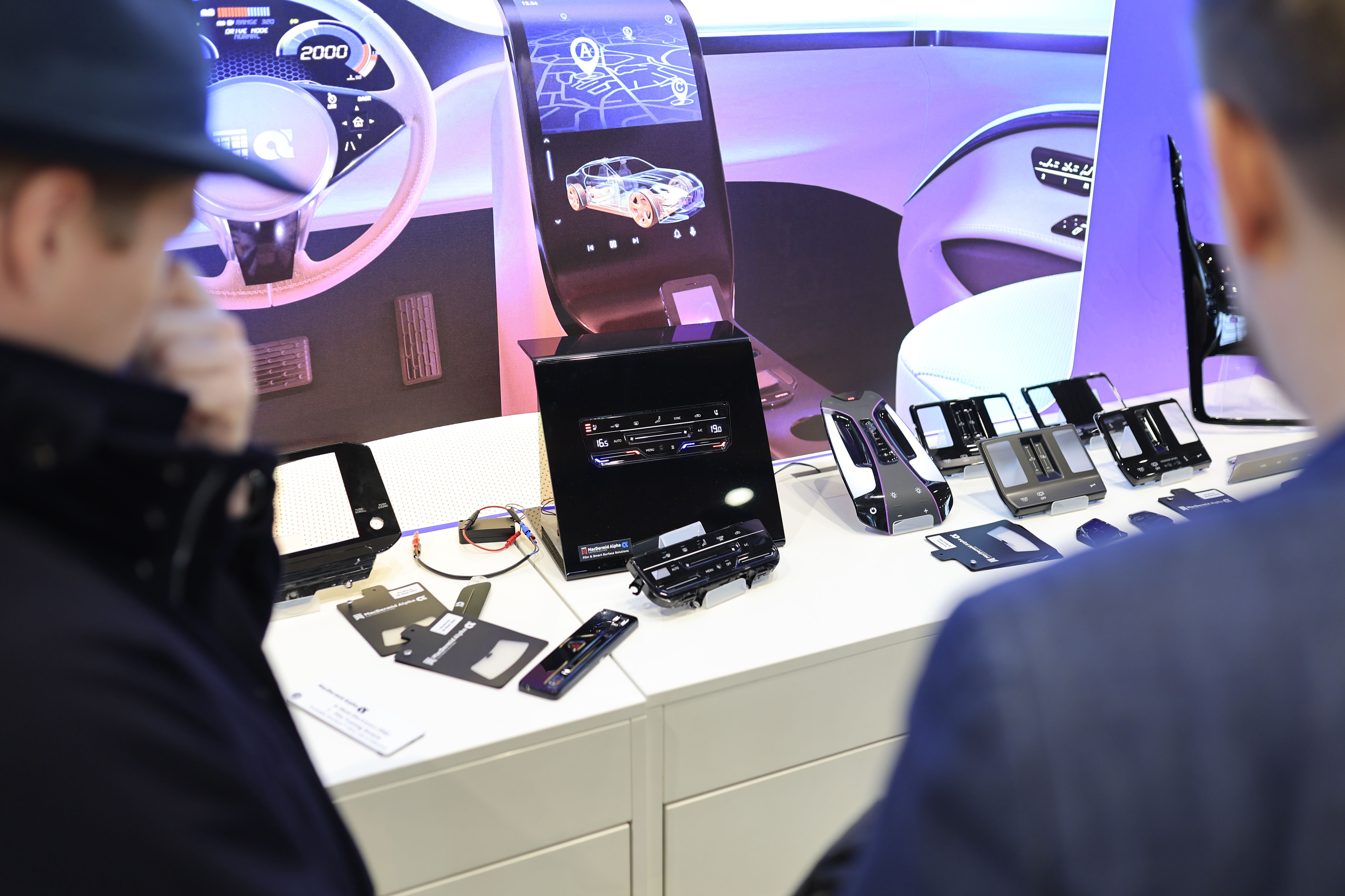 Photo shows visitors looking at the technology on display at Automotive Interiors Expo North America