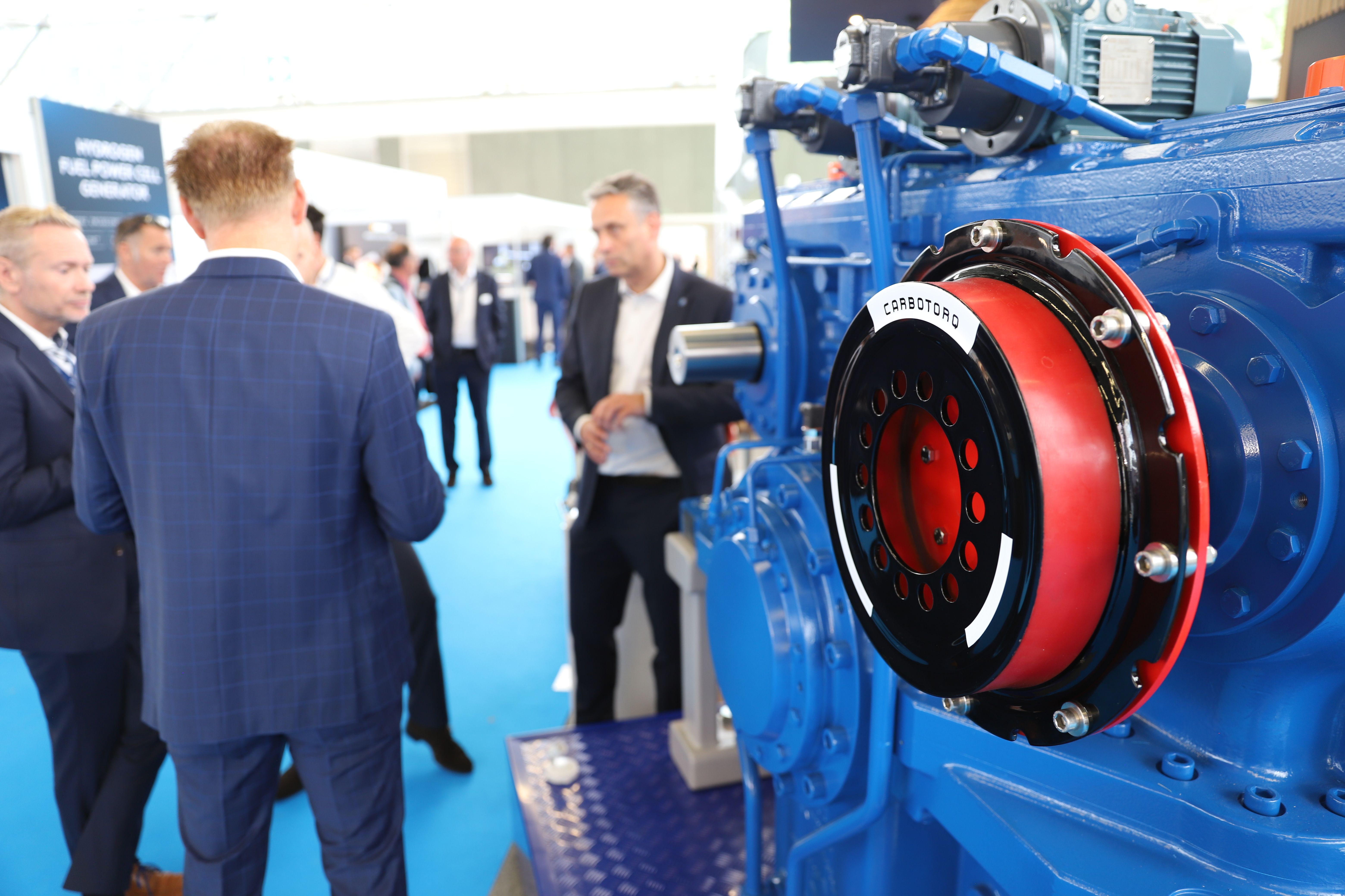 Photo shows a close up of technology on display at Electric & Hybrid Marine in Amsterdam with people networking in the background