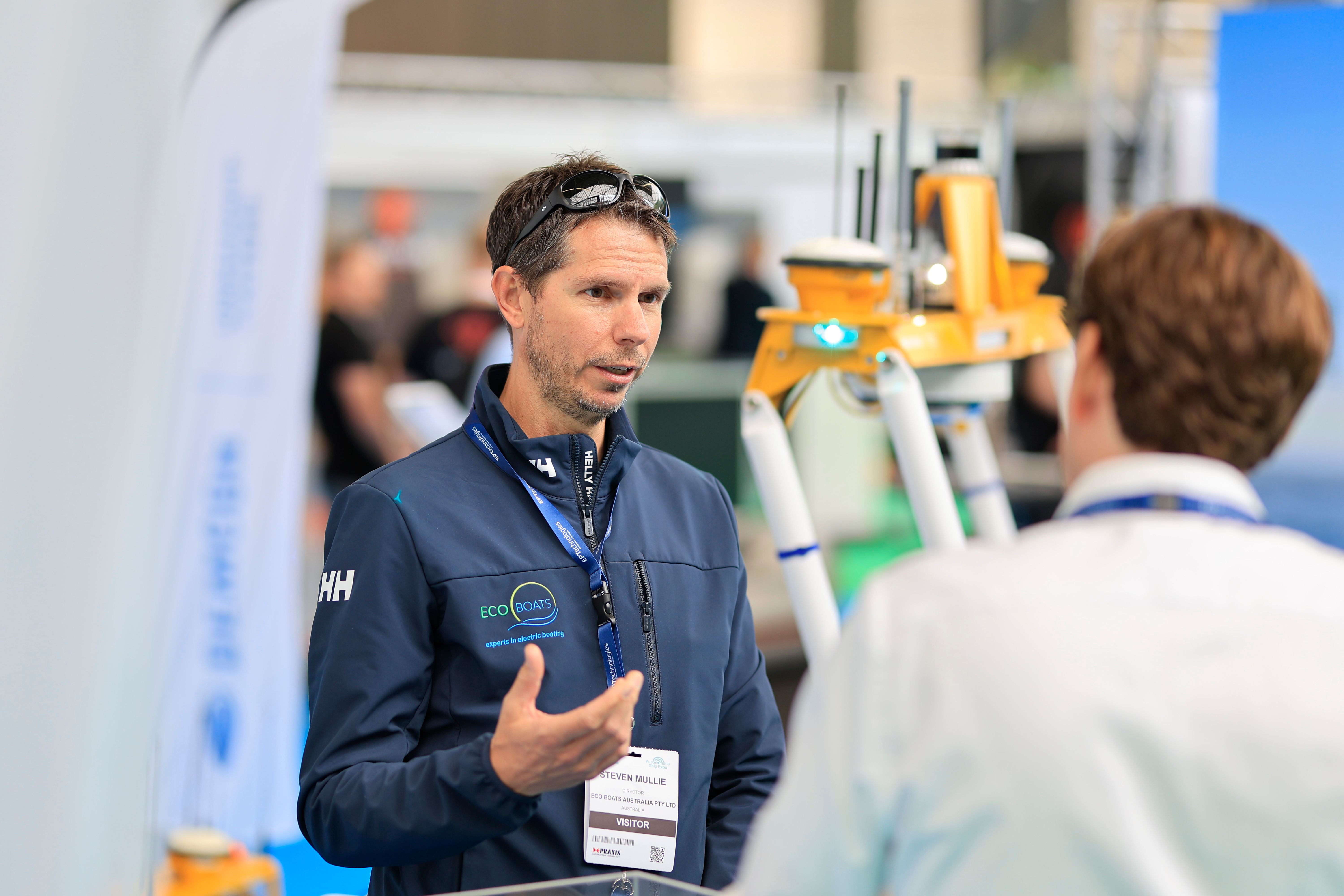 Photo shows an exhibitor and two visitors networking at Electric & Hybrid Marine Expo in Amsterdam