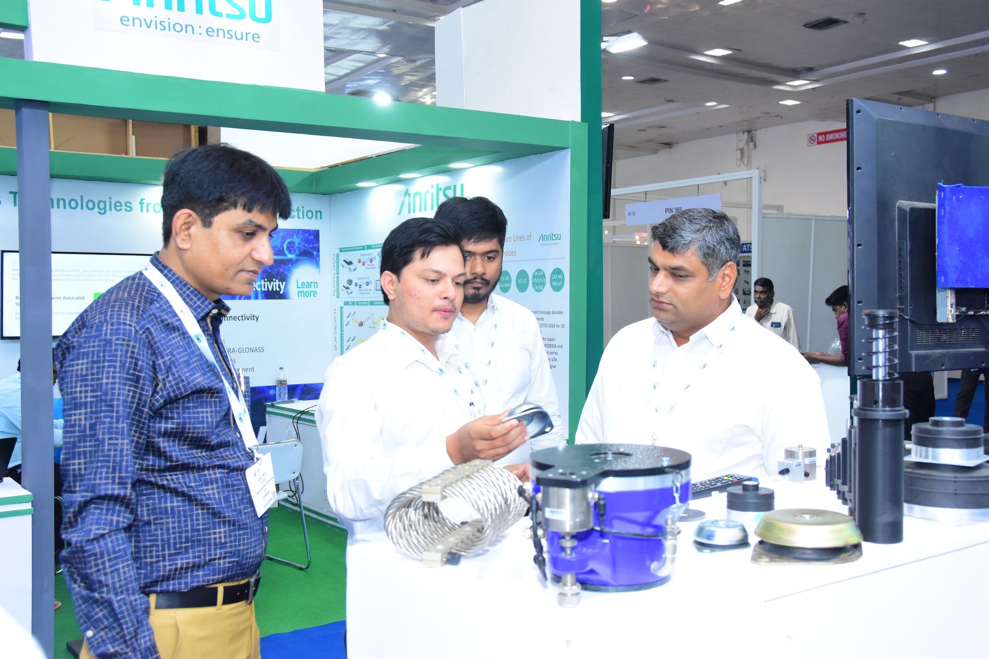 Photo shows an exhibitor of Automotive Testing Expo India discussing the technology they are showcasing on their booth to engaged visitors
