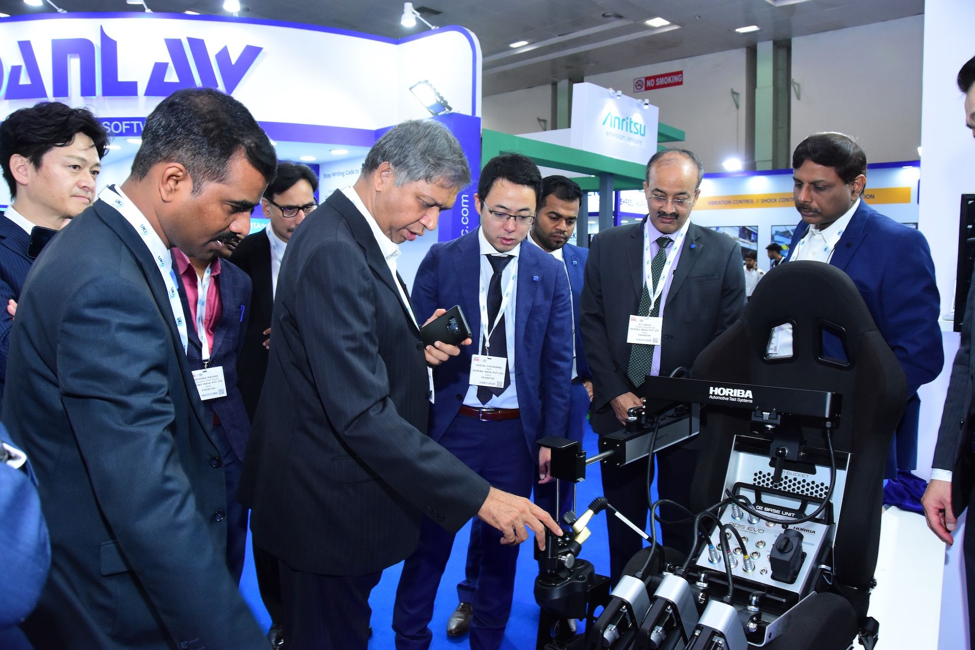 Photo shows a group of engaged visitors of Automotive Testing Expo India looking at the innovative technology on display on a booth