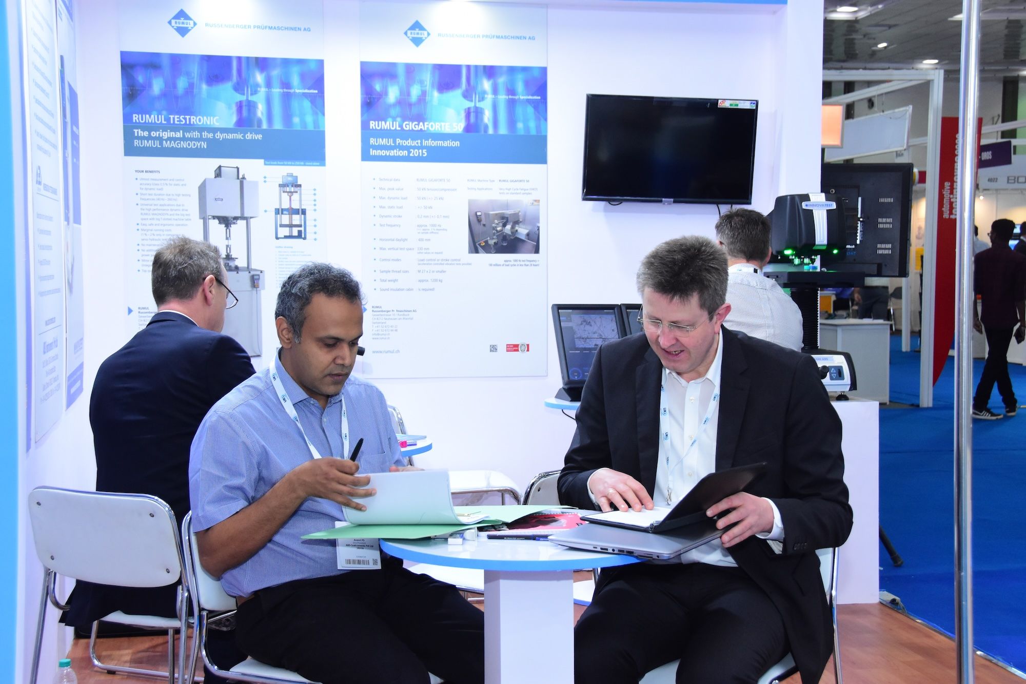 Image shows a booth at Automotive Testing Expo in Chennai, India with a visitor and exhibitor having a meeting