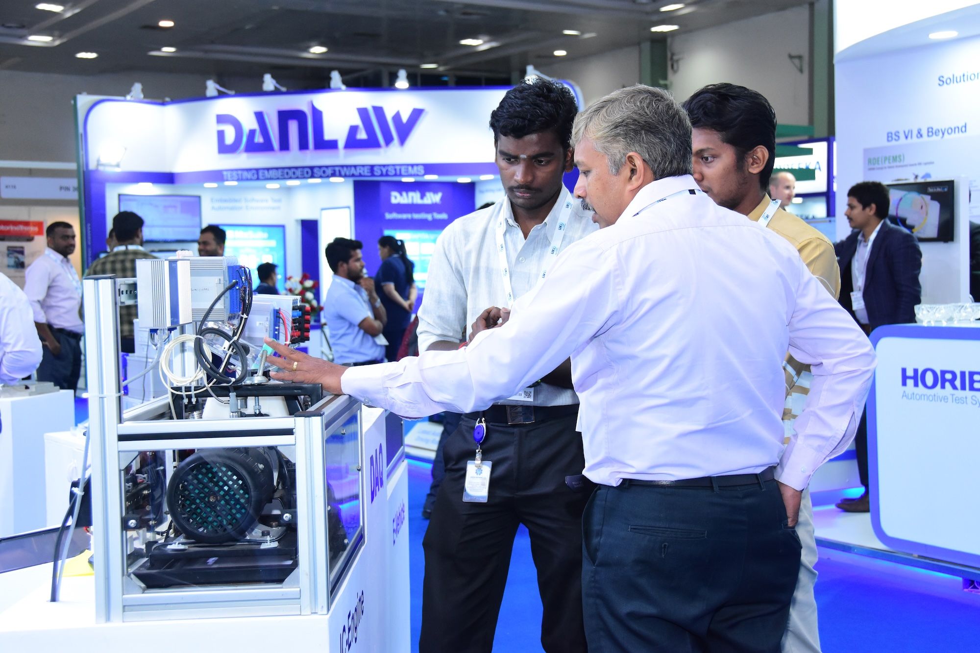 Photo shows an exhibitor of Automotive Testing Expo India talking through the technology on display on their booth with engaged visitors