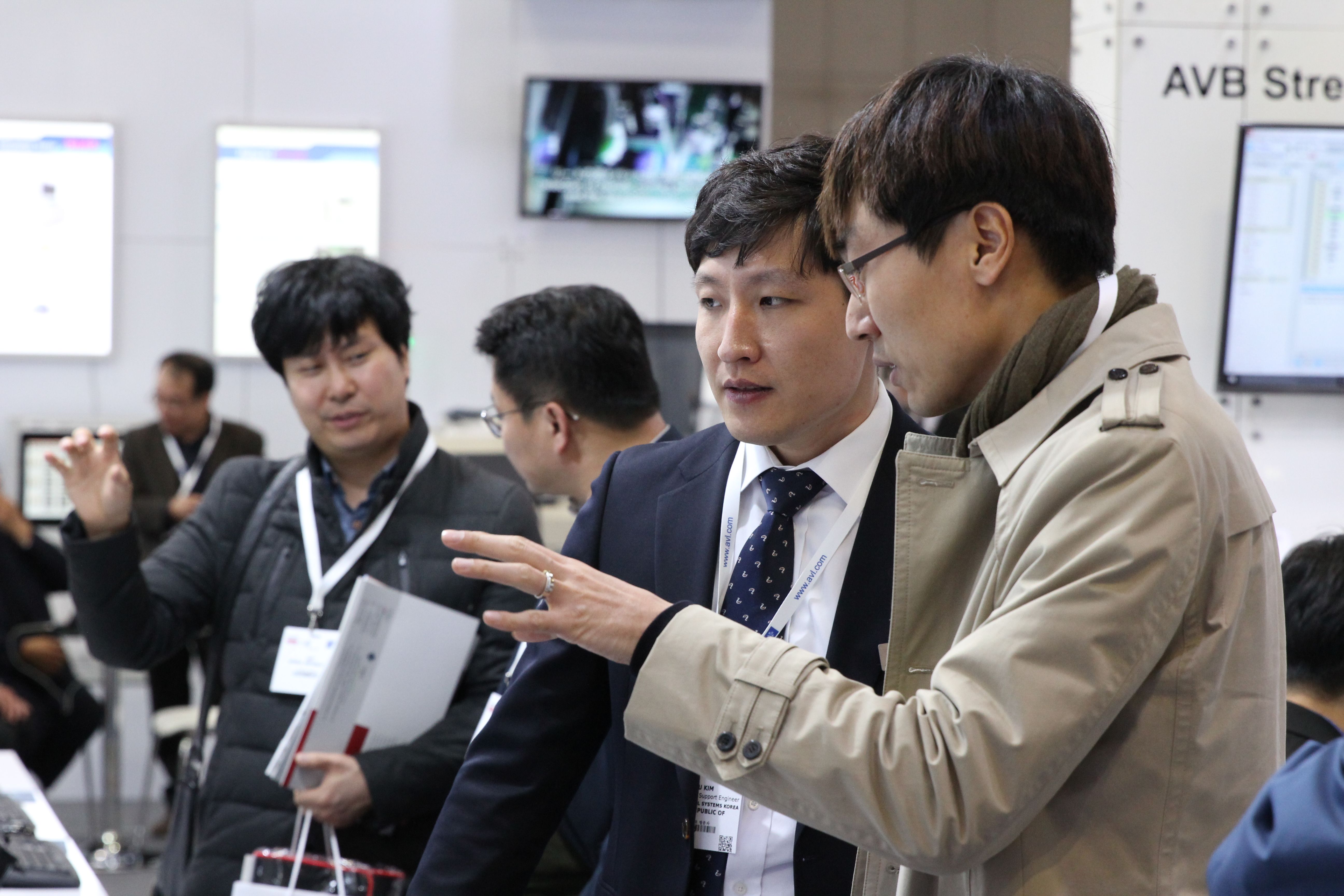 Photo shows visitors discussing the technology on display at Automotive Testing Expo Korea