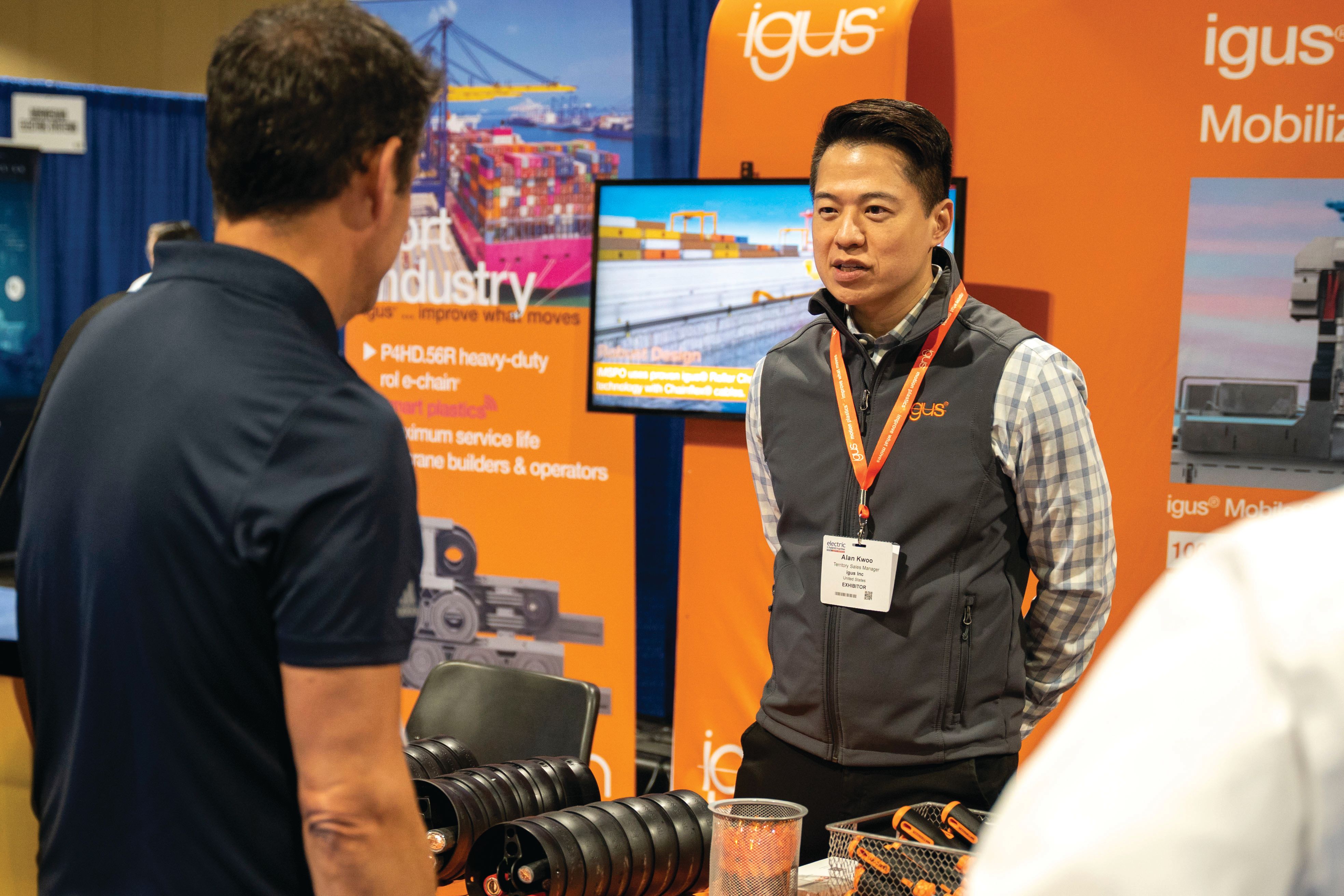 Photo shows an exhibitor talking to a visitor at Electric & Hybrid Marine Expo, North America