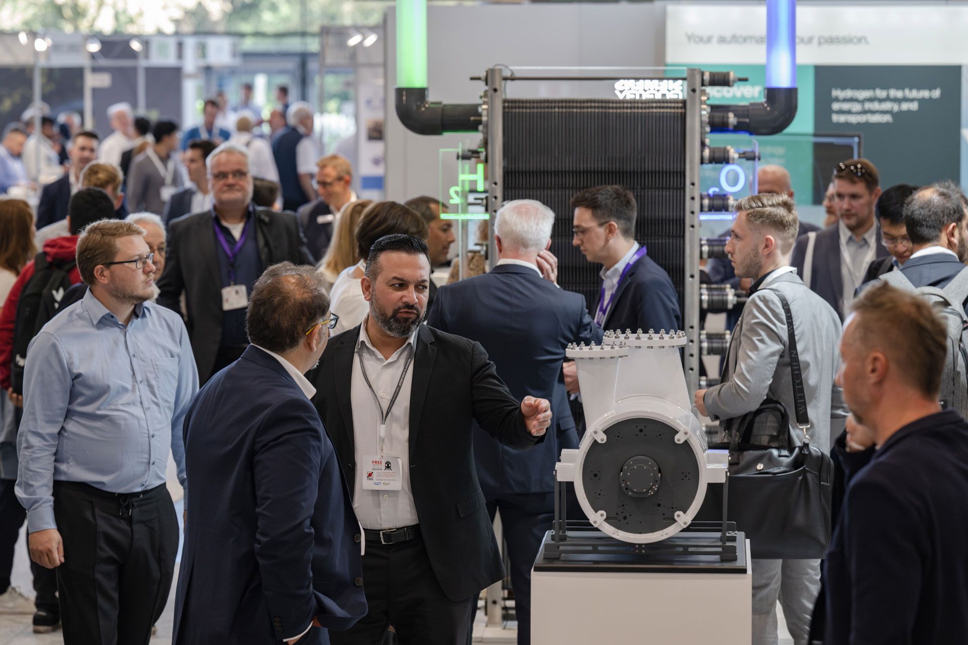 A busy expo floor with three visitor talking to an exhibitor 