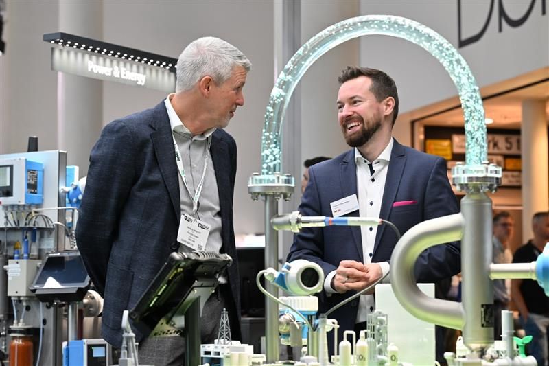 Two male expo visitors discussing and laughing on a stand 