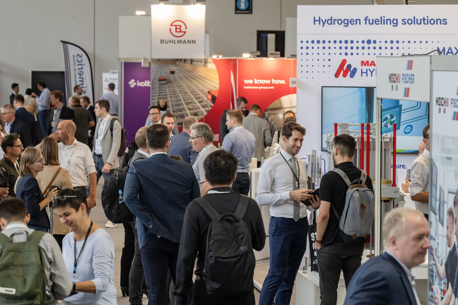 A busy expo floor with bright stand builds in the background