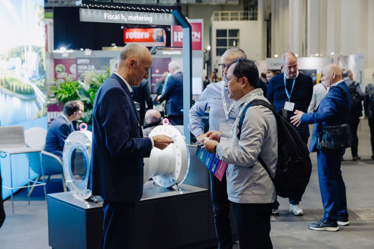 2 men and 1 woman in business suits looking at and discussing a display case on an expo floor related image