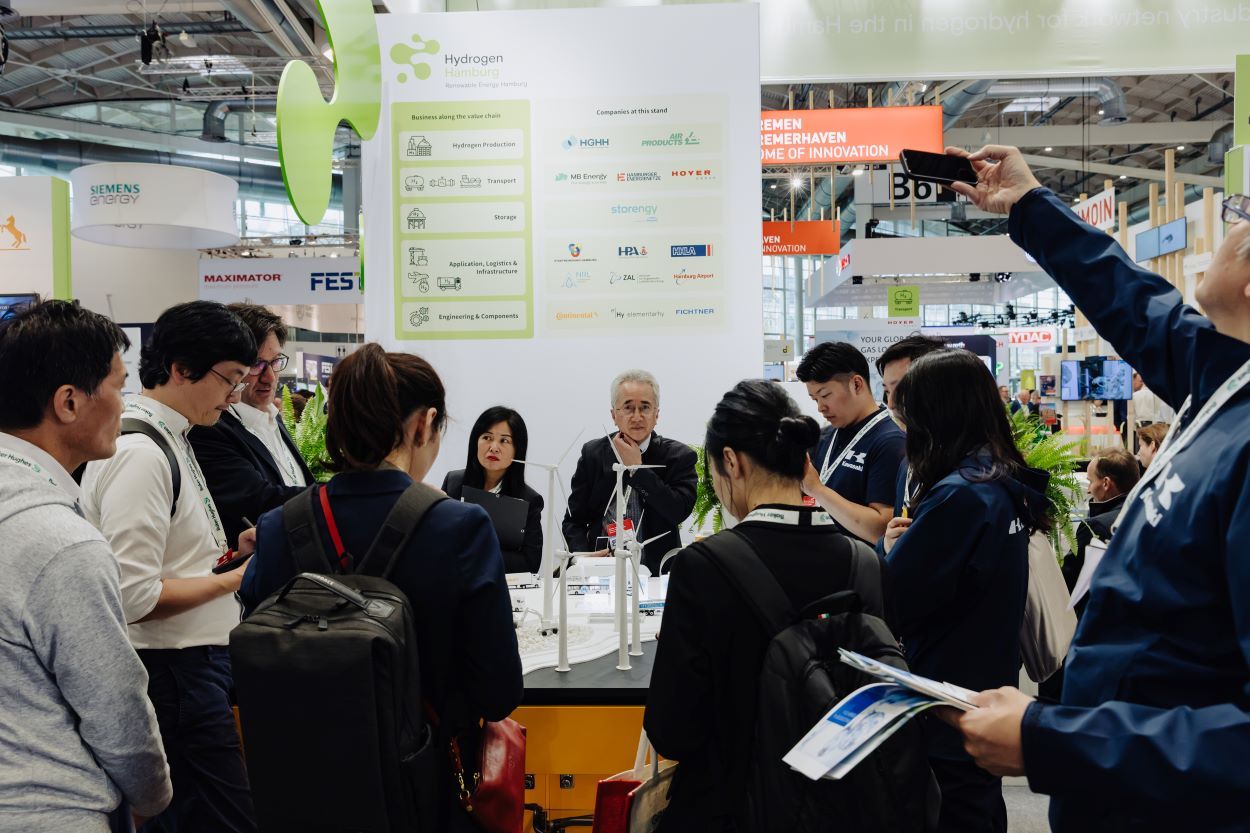 An image of expo visitors looking at a stand display in a busy expo hall