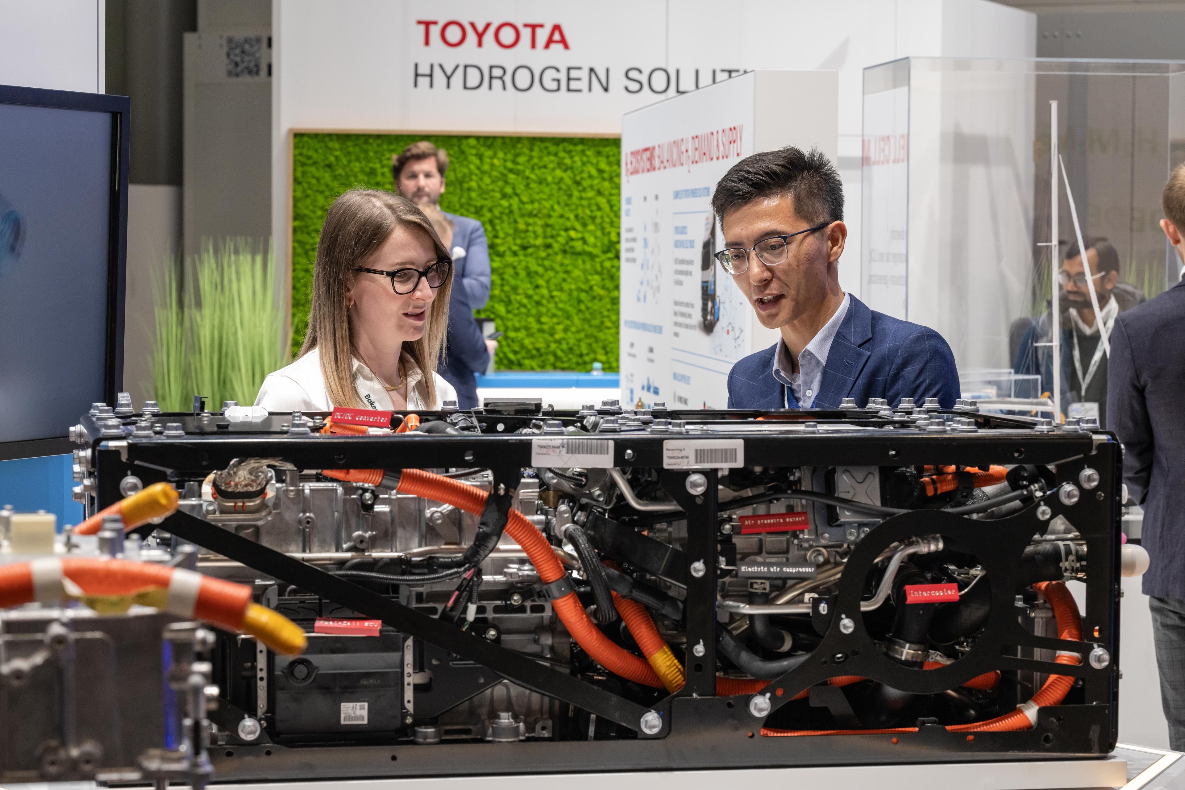 Two expo attendees at a stand looking at a piece of hydrogen technology
