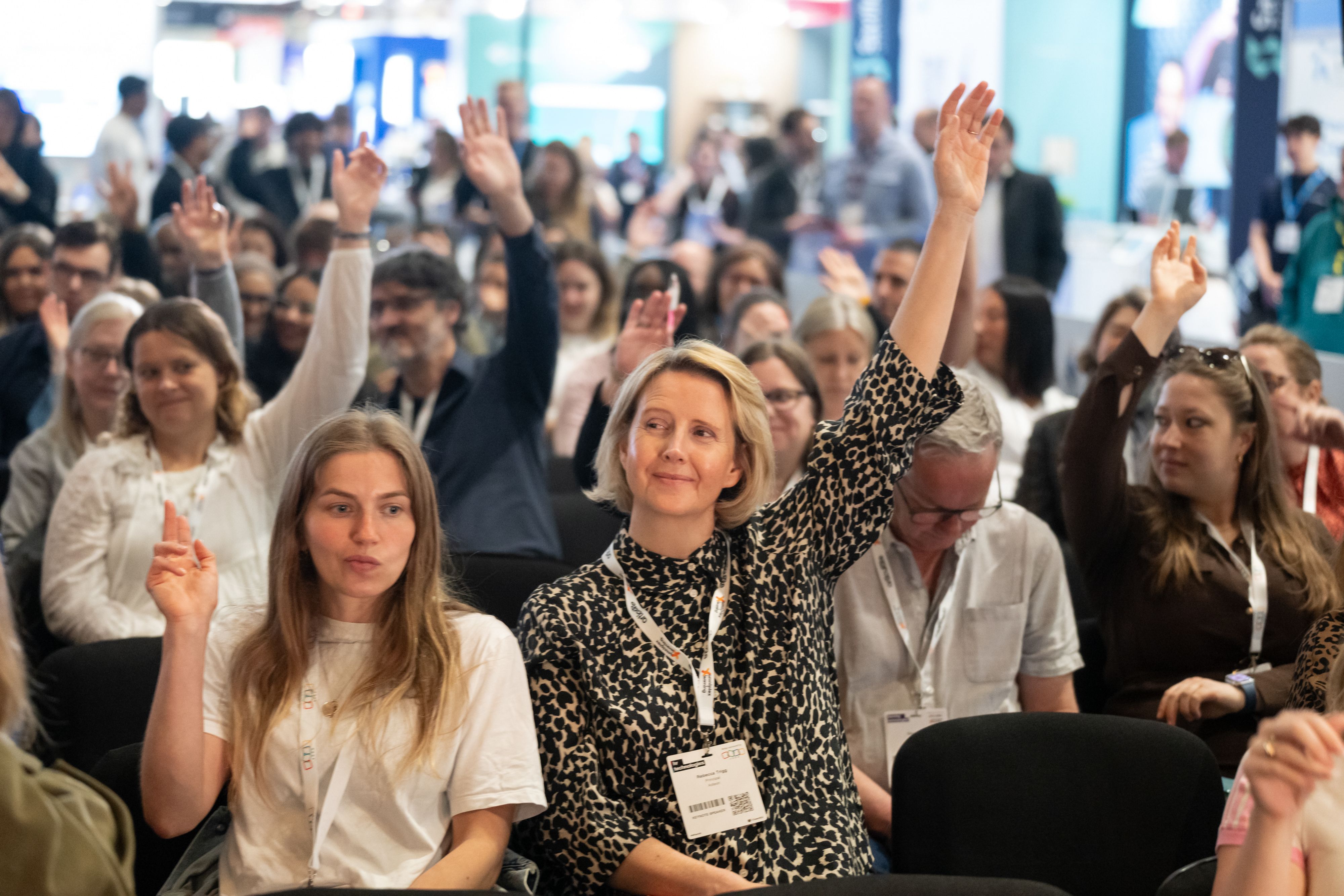 An audience of visitors raising their hands