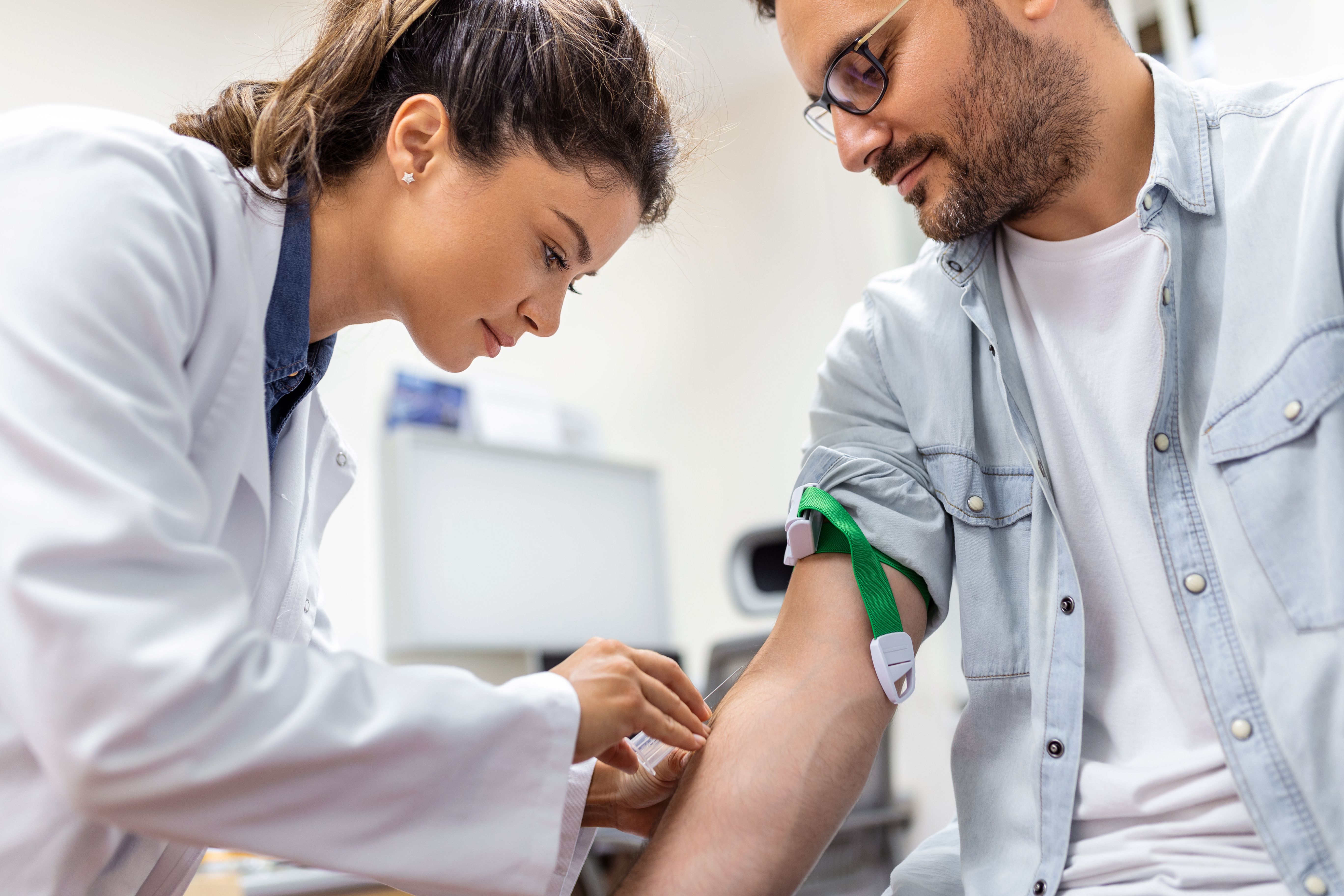 A phlebotomist preparing to draw blood from patients.