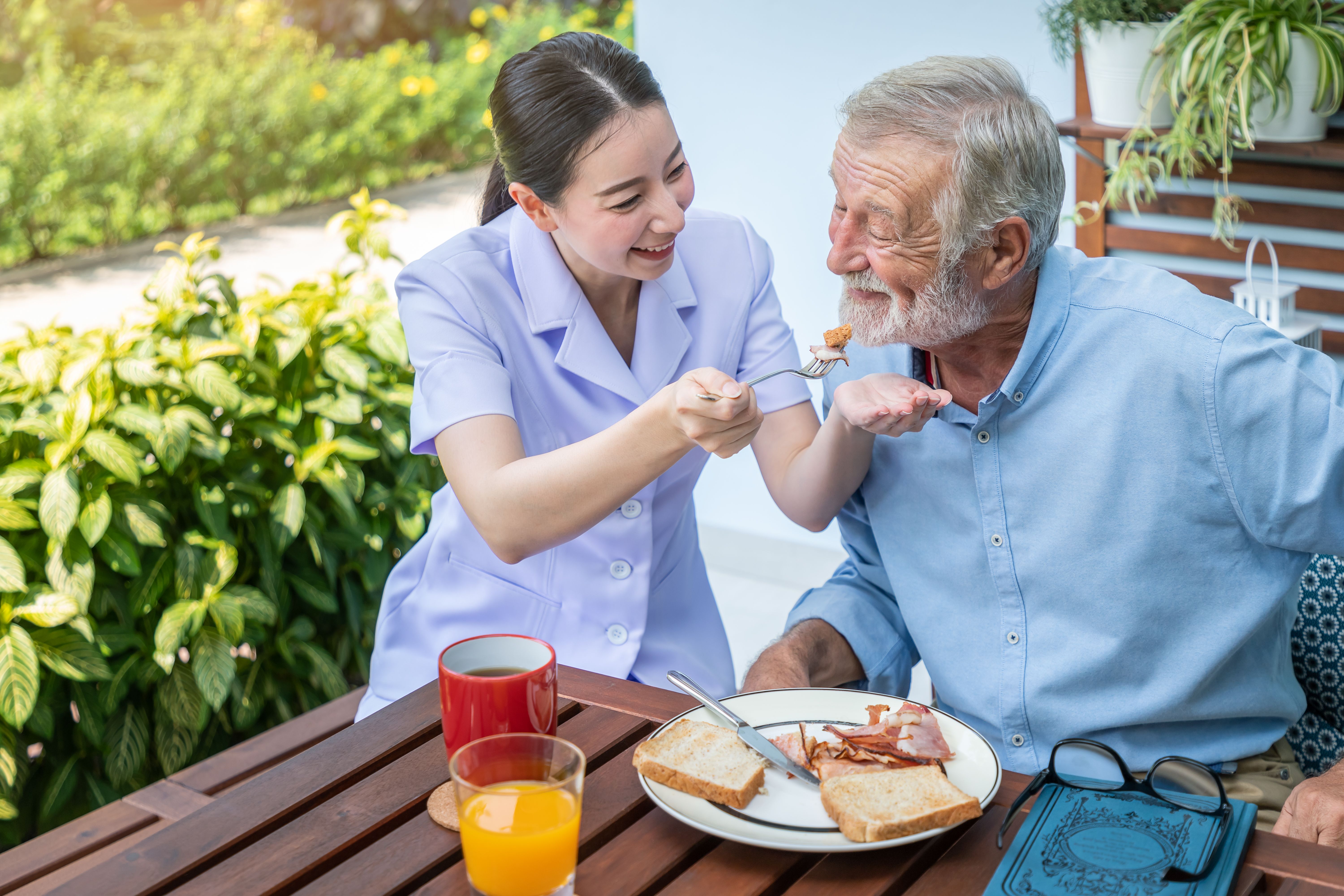 A nurse feeding an elderly patient in a nursing home.