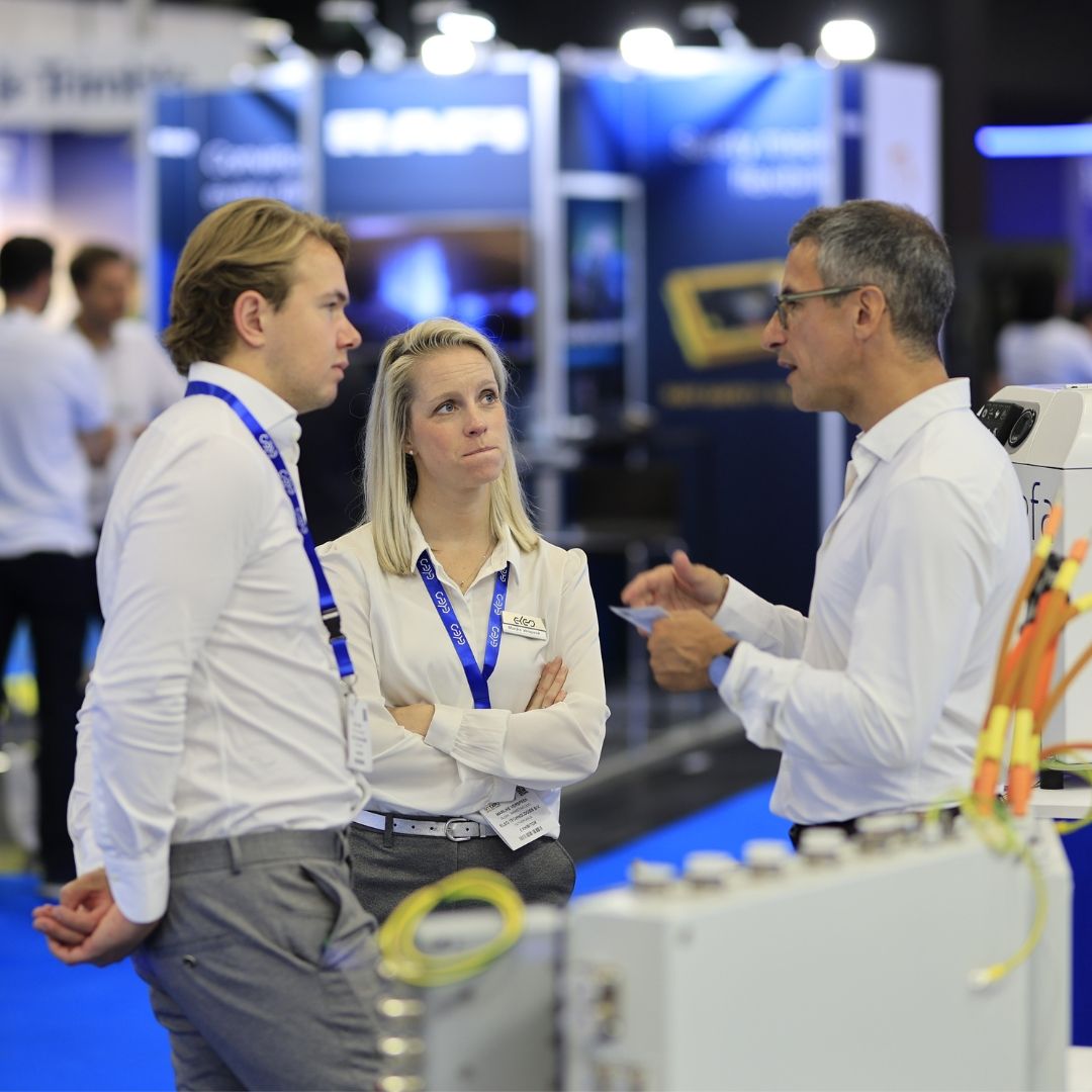 Photo shows three people, two men and a women deep in discussion at iVT Expo
