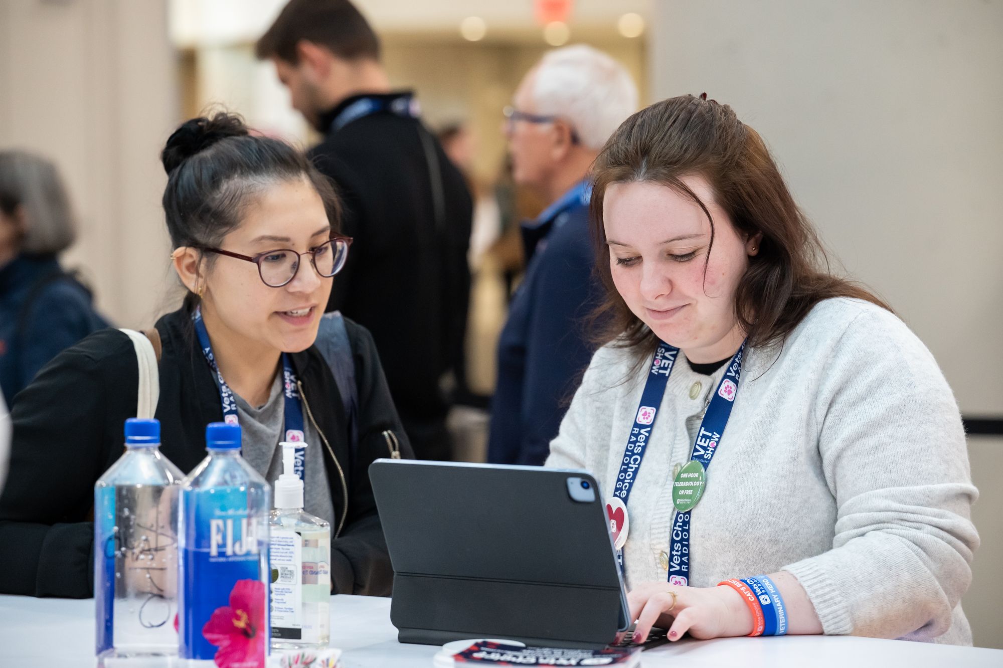 Two people sitting at a table, looking at an iPad and smiling