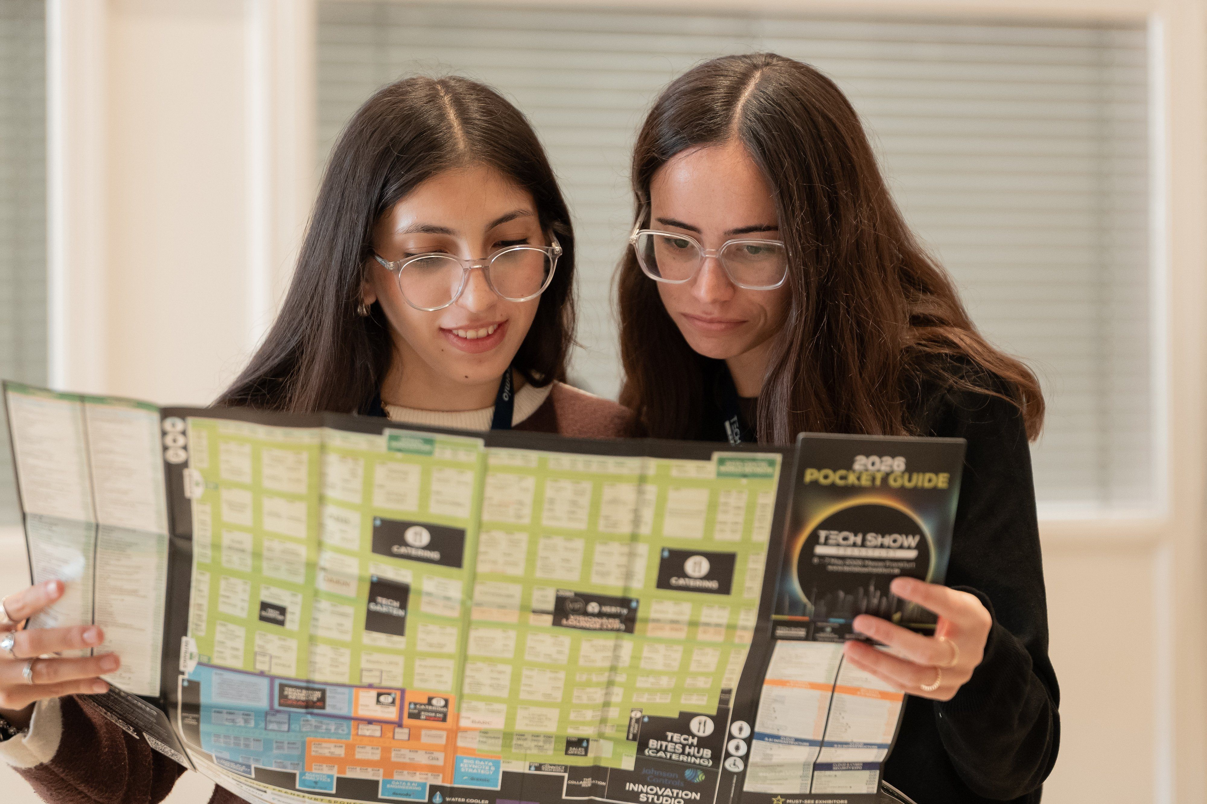 Two women looking at the Tech Show Frankfurt 2026 Pocket Guide.
