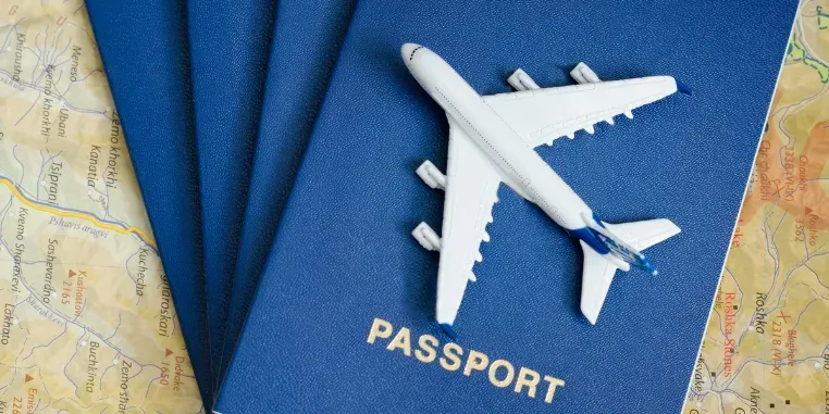 Toy airplane resting on fanned-out blue passports over a travel map.
