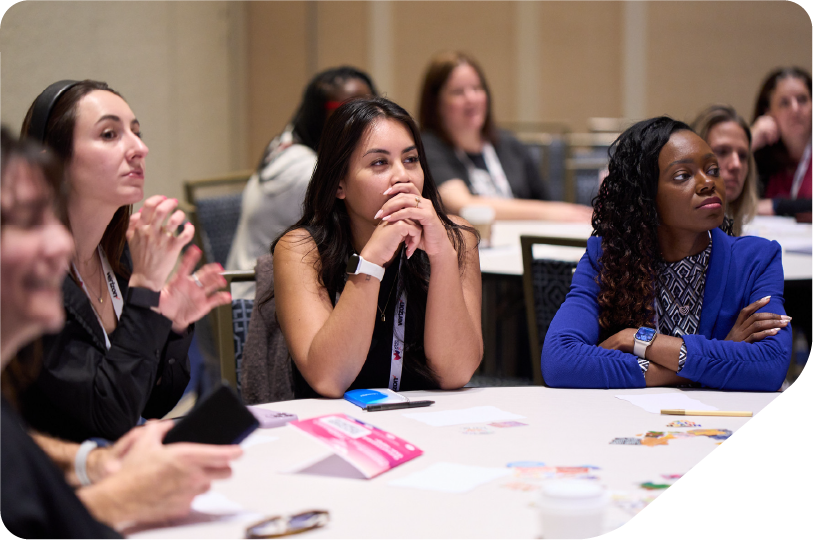 Image of a group of women huddled around a table working on a activity in an interactive workshop