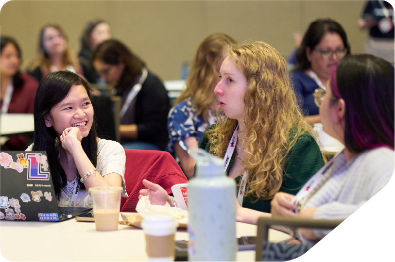 Image of a group of women writing down on a sheet of paper and laptops as part of a workshop activity