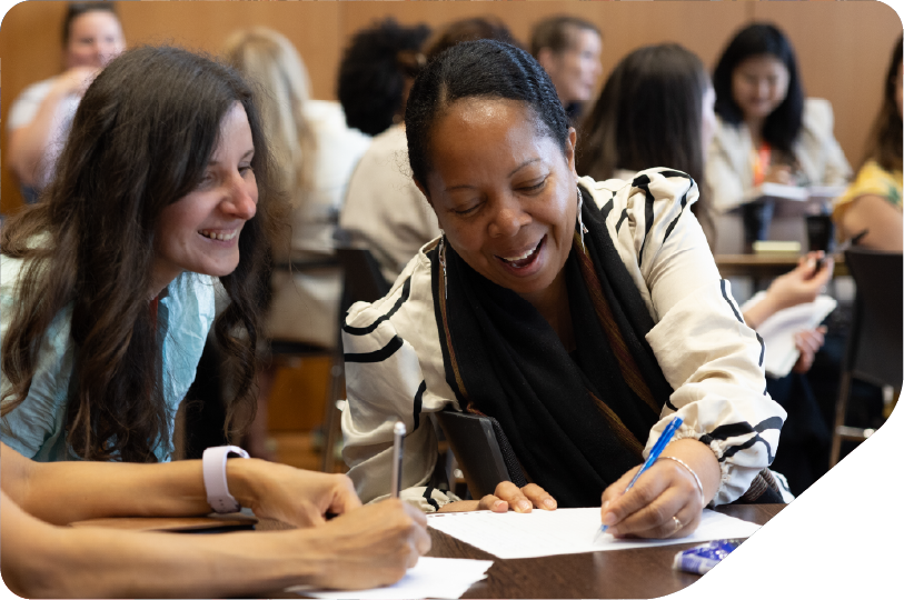 women sat around table with laptop, tables and workshop sheets problem solving