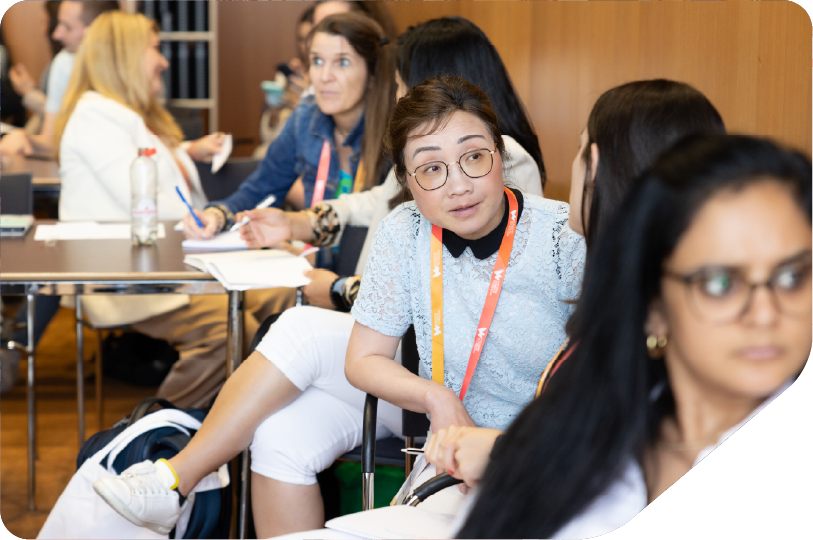 women sat around table with laptop, tables and workshop sheets problem solving