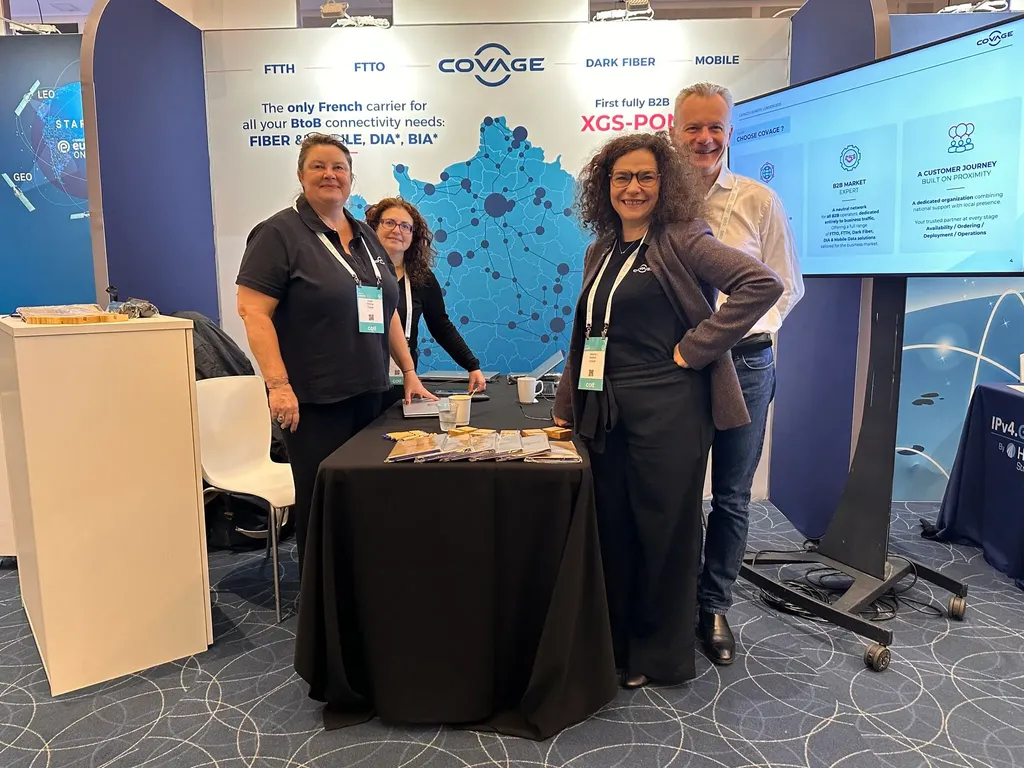 The Covage team standing proudly at their exhibition booth featuring a large map of France and signage for Dark Fiber and Mobile connectivity solutions at Capacity Europe.