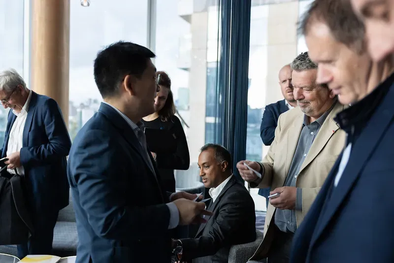 A professional business meeting taking place at the Gamma booth during Capacity Europe, with attendees seated in a branded lounge area discussing business.