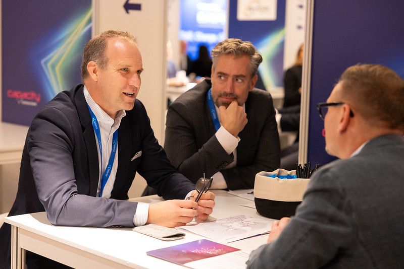 Three gentlemen sitting on a table having a discussion