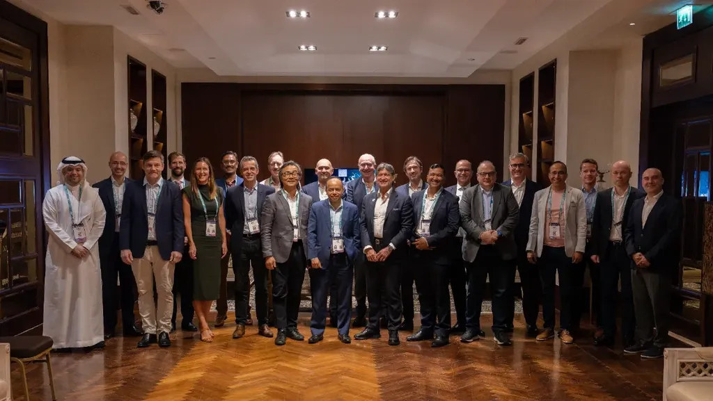 A large group of corporate executives and digital infrastructure leaders posing together for a group photo in a formal meeting room at the MENA Digital Infra Leaders Summit.