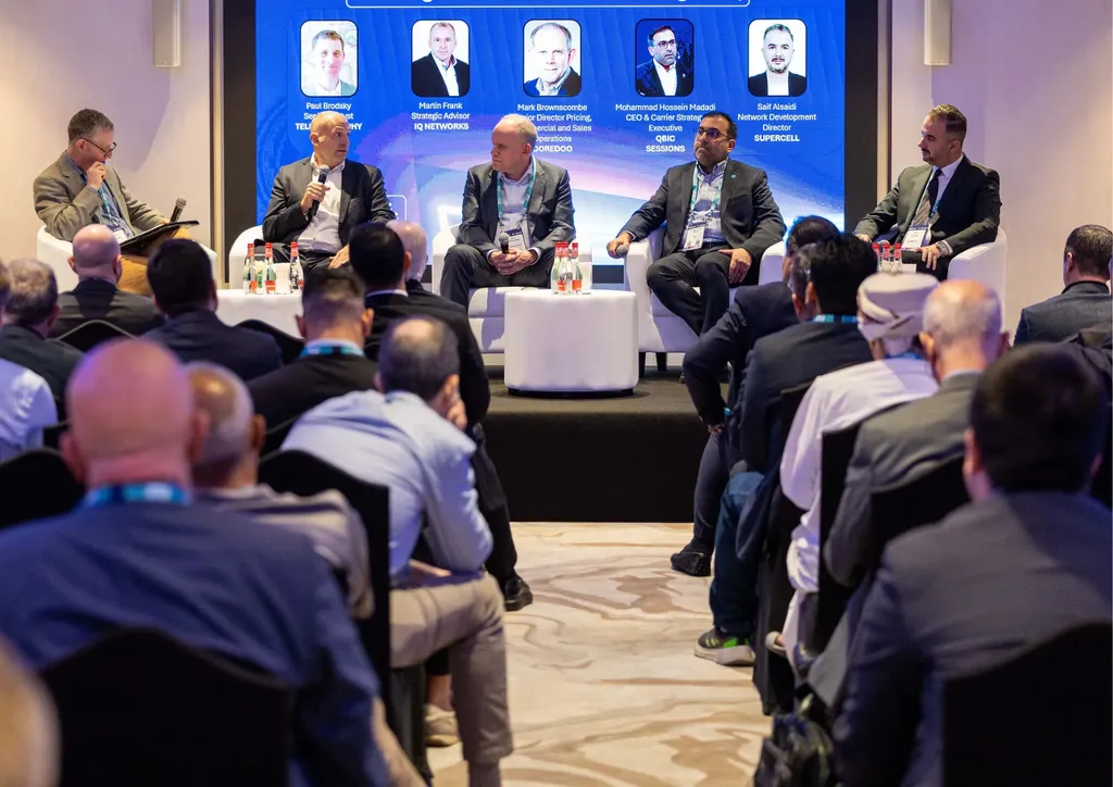 Five-person industry panel on stage at a telecoms conference, with speakers in white armchairs in front of a packed audience.