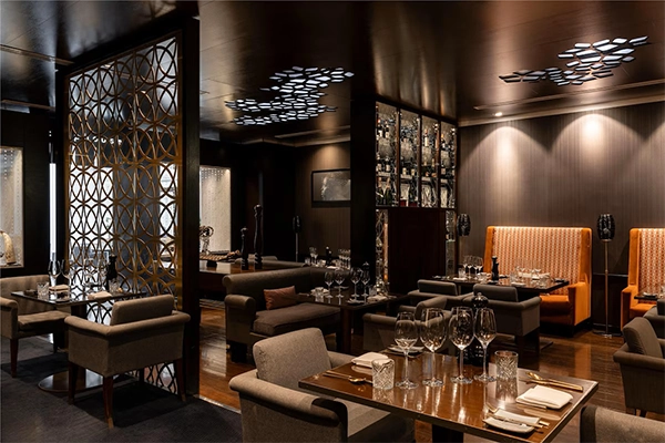 Interior dining room of Chophouse restaurant with modern dark decor, formal table settings, plush seating, and decorative gold partition screens.