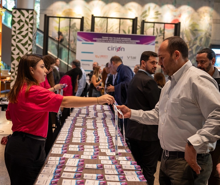 Registration staff handing event badges and lanyards to attendees at the Capacity LATAM conference.