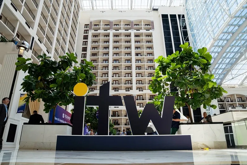 A wide-angle, low-perspective photograph inside a massive hotel resort atrium featuring a large, free-standing black sculpture of the lowercase letters 