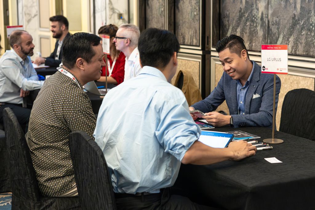 Attendees taking part in scheduled business meetings at branded meeting tables during a networking event.