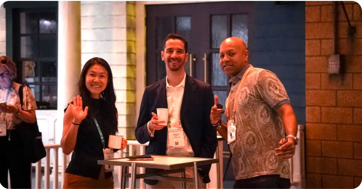 Three Metro Connect attendees gathering around a table during the Fiber Leaders Lunch, with drinks and event badges visible.
