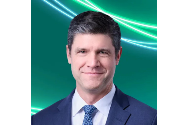 Professional headshot of Jason Hill, with short, styled dark grey hair, wearing a dark blue suit jacket, a white shirt, and a blue patterned tie. The background is teal with glowing green and white abstract lines curving across the top.