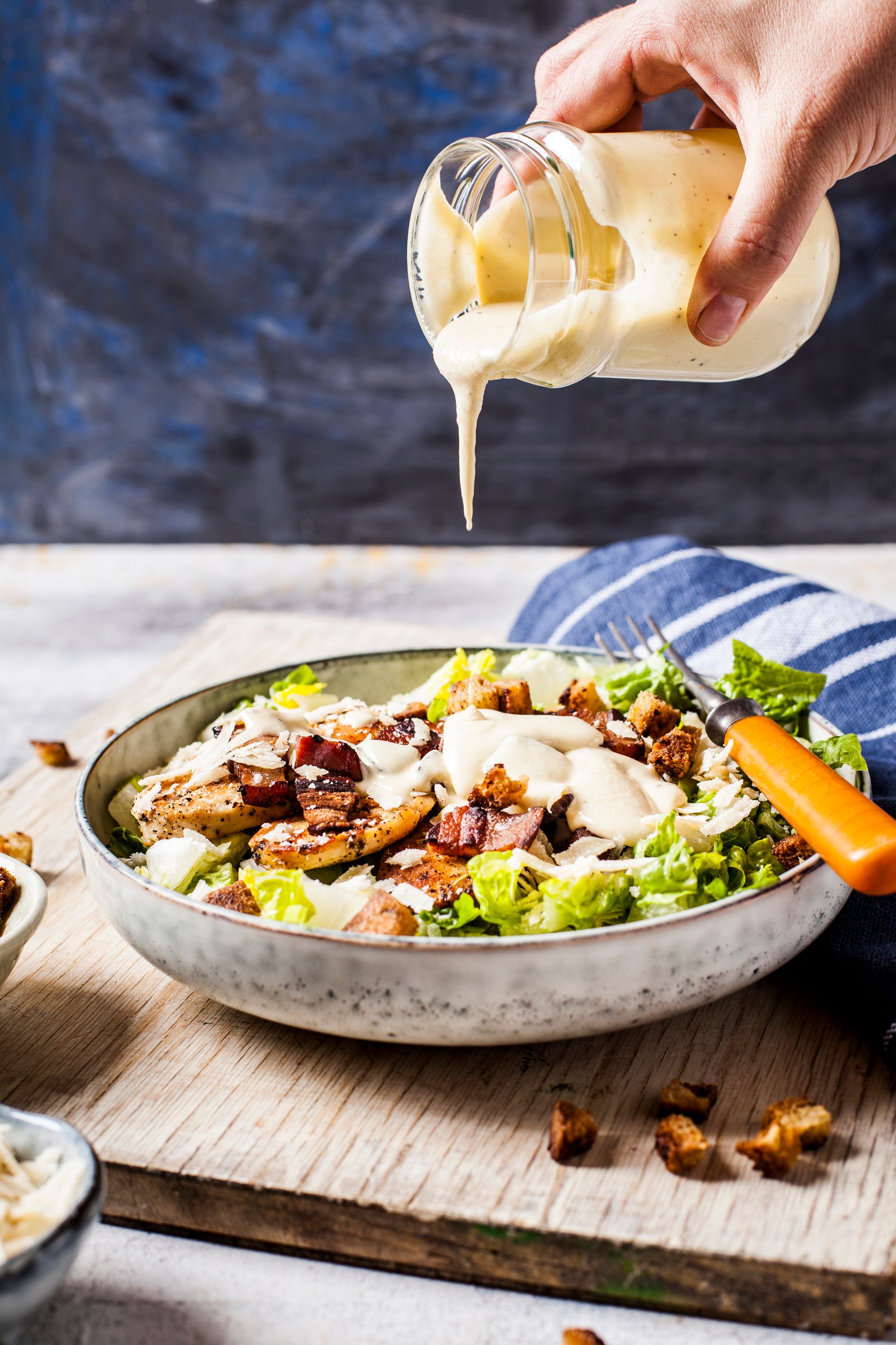 condiment being poured on salad