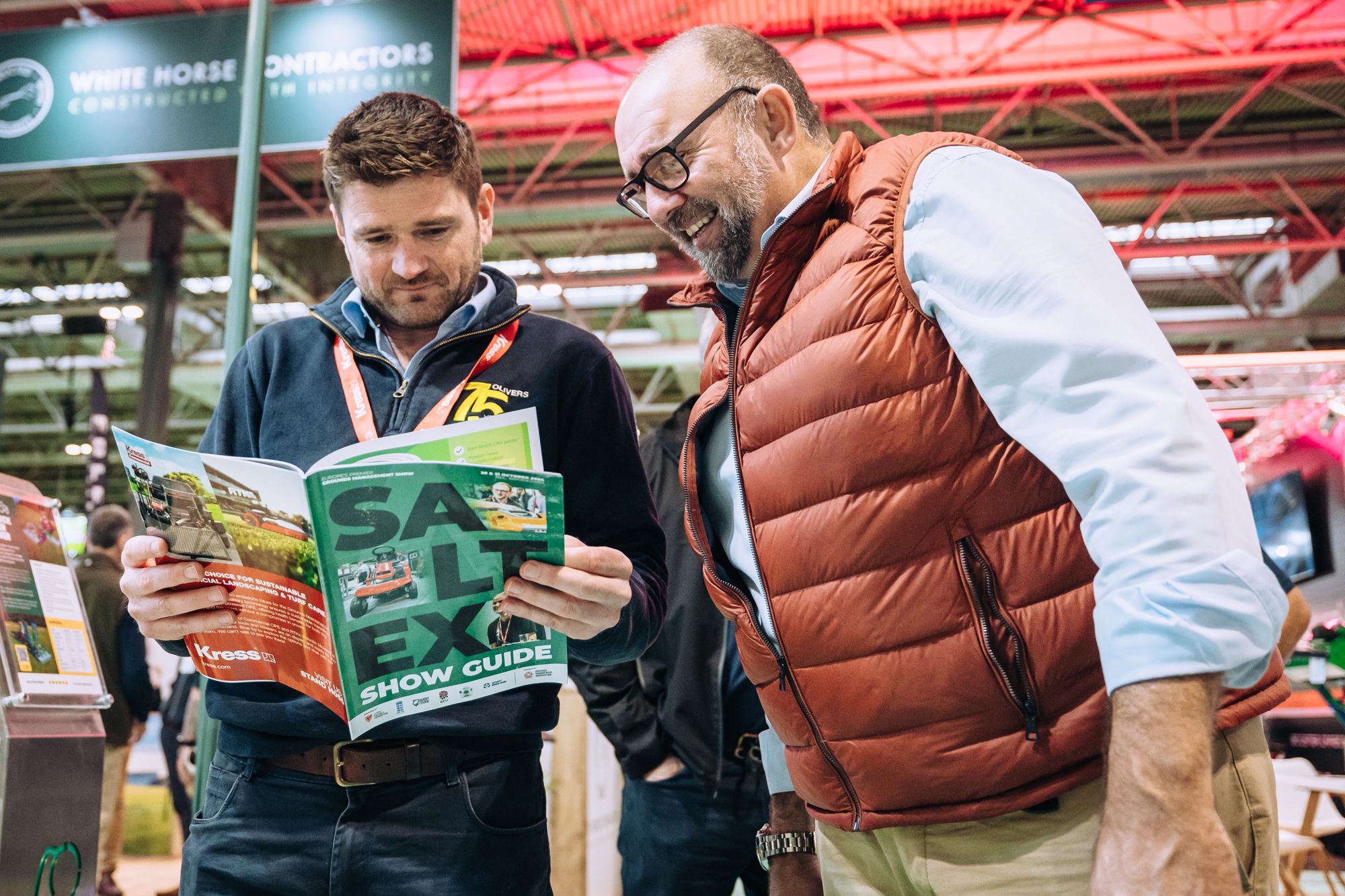 Two men looking at event guide smiling
