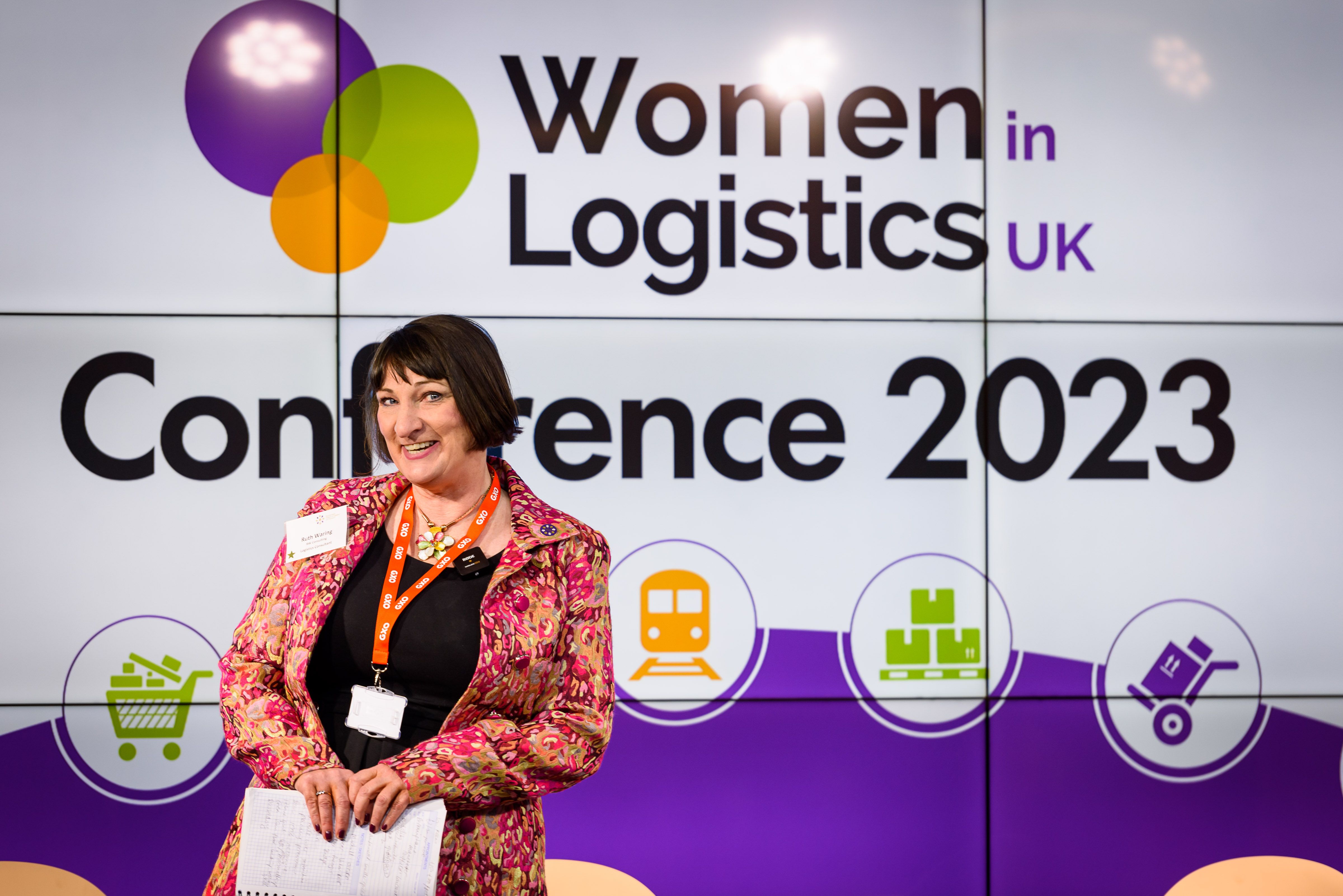 Ruth Waring pictured in front of 2023 Women in Logistics UK Conference logo
