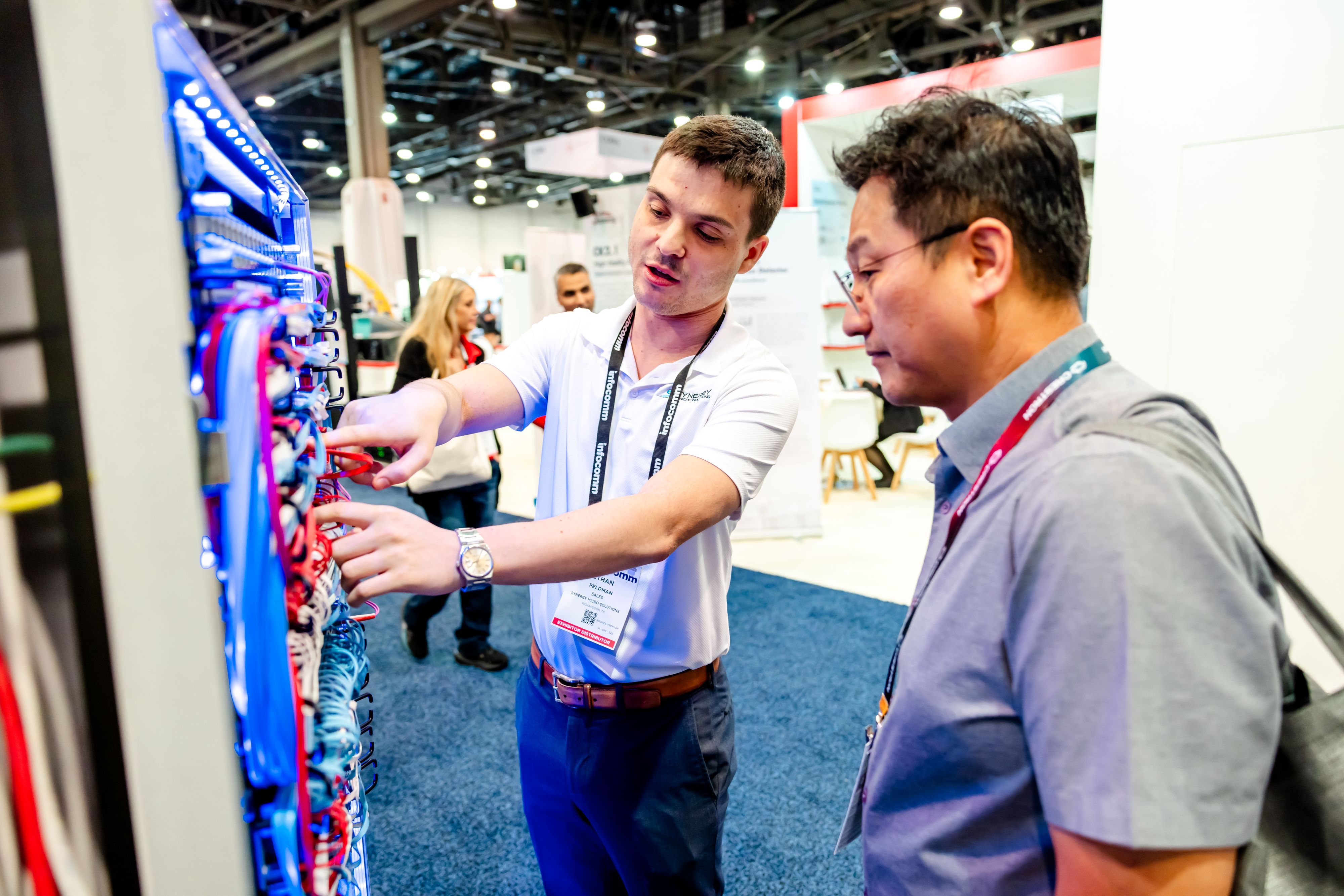 InfoComm exhibitor and visitor observe a cable assembly.