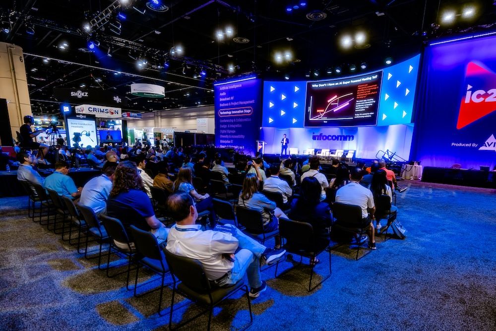 A large crowd sits around the Technology Innovation Stage at InfoComm